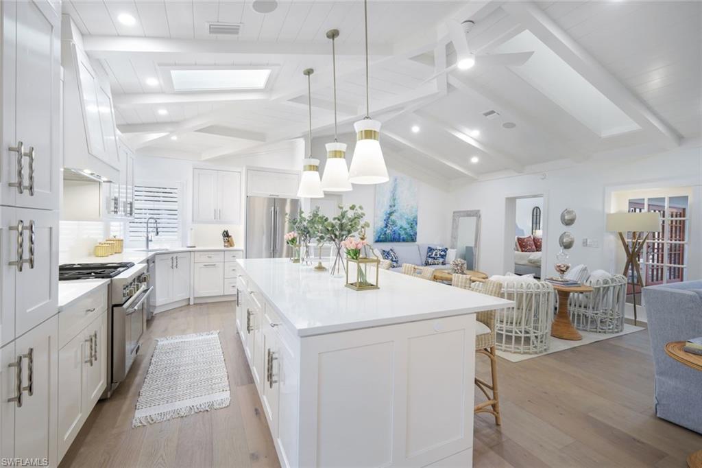 67 8th Avenue South Naples, FL 34102 - Photo 9 of 38 a kitchen with stainless steel appliances kitchen island granite countertop a stove top oven a sink a dining table and chairs with wooden floor