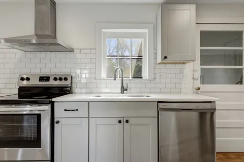 a kitchen with granite countertop a sink stainless steel appliances and cabinets