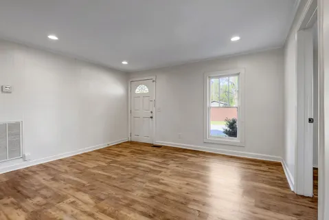an empty room with wooden floor and windows