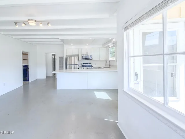 a large white kitchen with kitchen island and a large window
