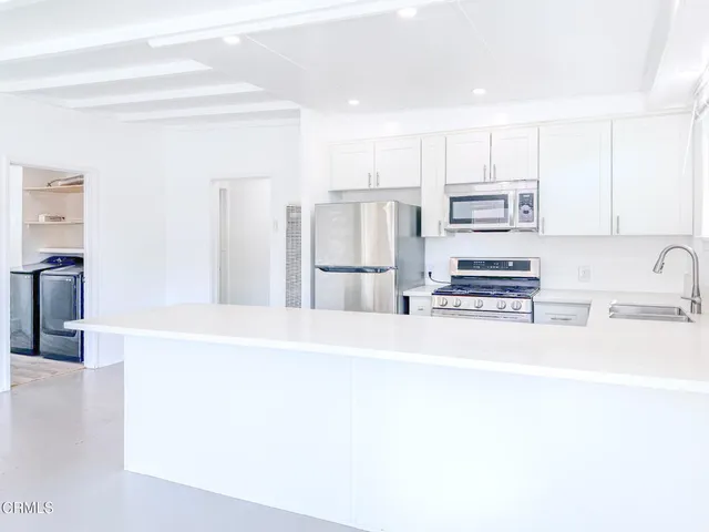 a kitchen with stainless steel appliances kitchen island sink refrigerator and stove