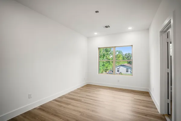 an empty room with wooden floor and window