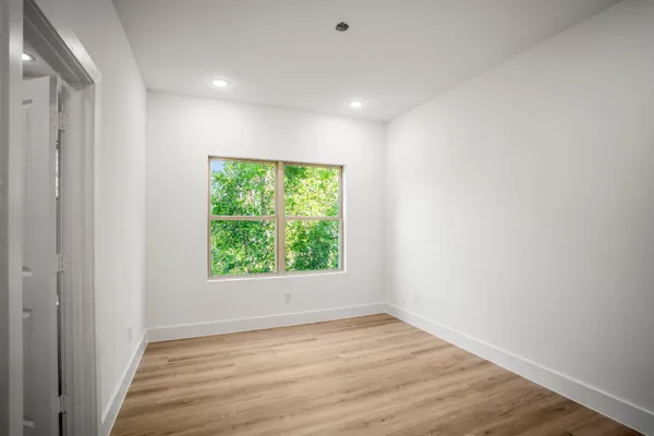 a view of an empty room with wooden floor and a window