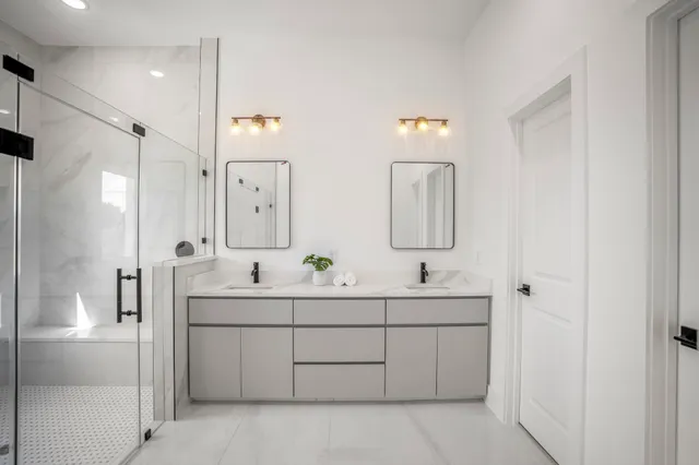 a bathroom with a double vanity sink mirror and shower
