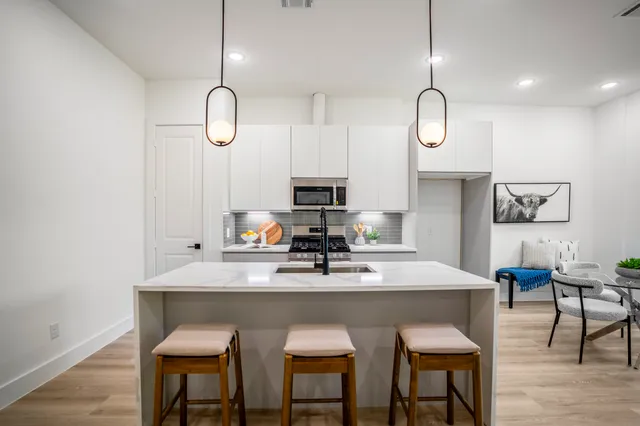 a kitchen with a dining table chairs and white cabinets
