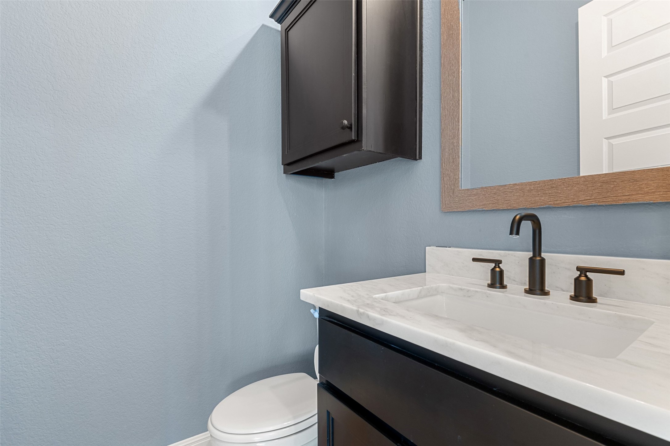 5420 Destination Way Jonestown, TX 78645 - Photo 27 of 39 A well-appointed powder room features a sophisticated dark vanity and a natural wood-framed mirror.