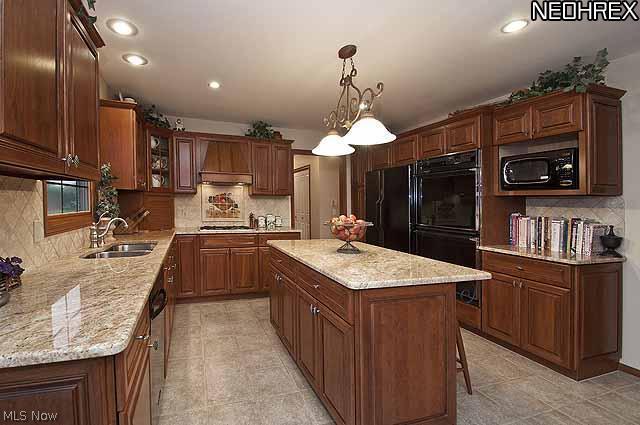 357 Longspur Road Highland Heights, OH 44143 - Photo 2 of 22 Cookâ??s dream kitchen featuring custom honey-stained cherry wood cabinets with maple interiors, gorgeous granite countertops, travertine tile backsplash, stainless steel Jenn-Air gas cooktop, large electronic double ovens, LG microwave, Kitchen Aid dishwasher, large stainless steel Kohler extra deep double sink with sprayer, appliance garage, glass front cabinet, cabinets/double pantry with pullout shelves, and a large island with eating space, walk-in bay with French door slider in breakfast room