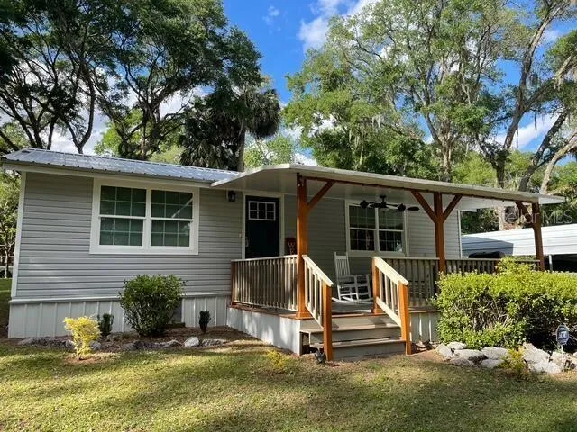 a view of backyard with a deck and a large tree