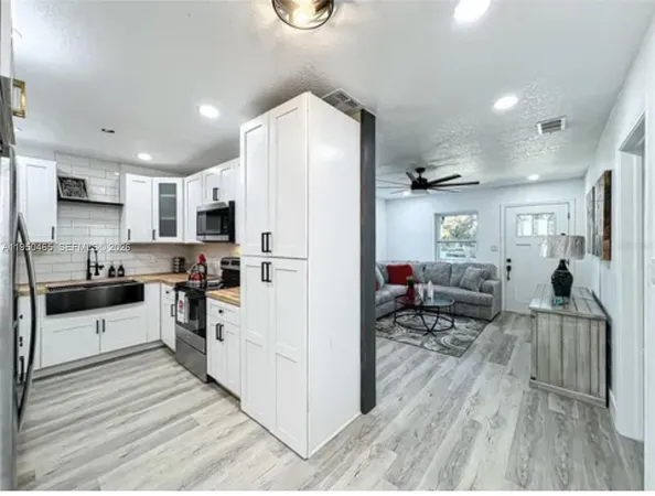 a kitchen with a refrigerator a stove top oven a dining table and chairs with wooden floor