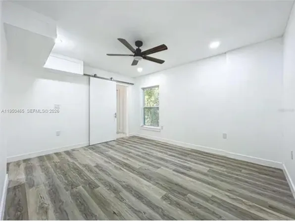 a view of empty room with wooden floor and ceiling fan
