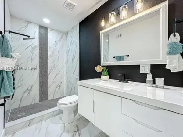 a bathroom with a sink a toilet and shower