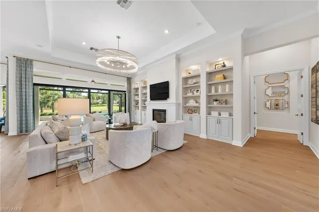 a large room with stainless steel appliances kitchen island granite countertop furniture a large window and a chandelier