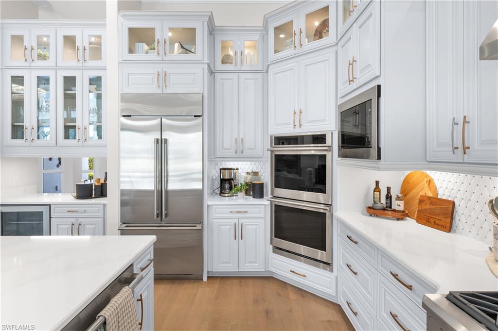 15266 Arpino Court Naples, FL 34114 - Photo 8 of 48 a kitchen with cabinets stainless steel appliances and wooden floor