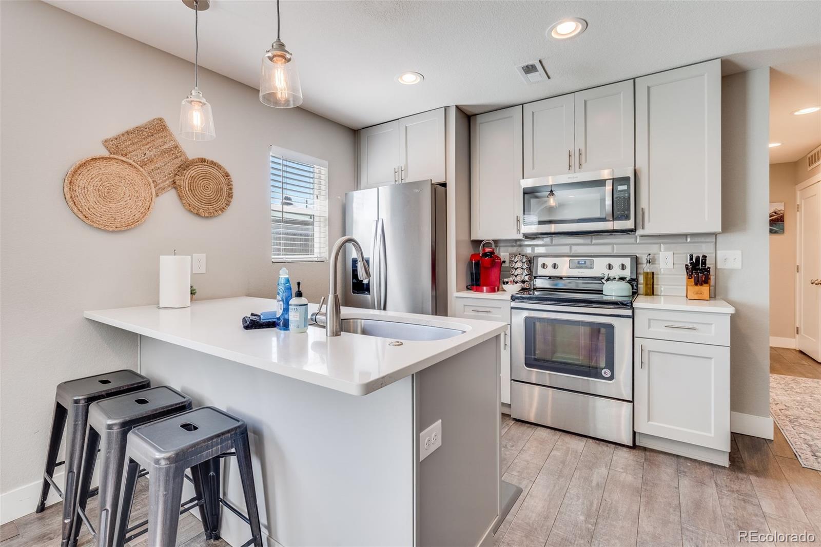 5240 Stuart Street Denver, CO 80212 - Photo 25 of 42 a kitchen with stainless steel appliances granite countertop a sink a stove a refrigerator cabinets and chairs