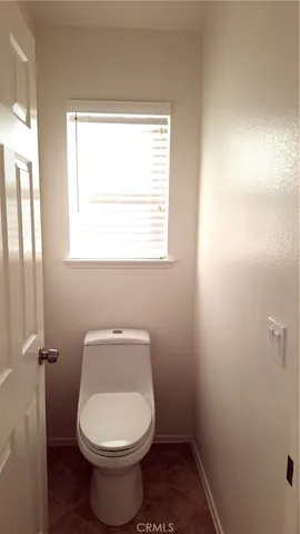 a white toilet sitting in a bathroom next to a window