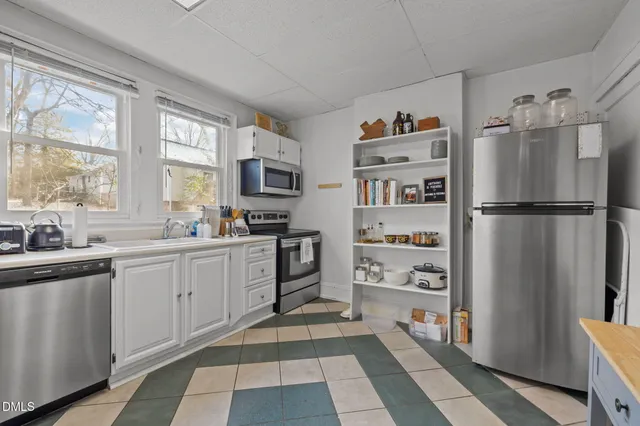 a kitchen with stainless steel appliances a sink a stove and white cabinets