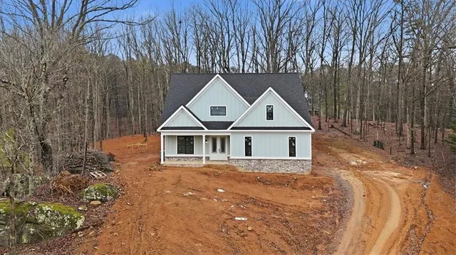 front view of house with a yard and trees all around