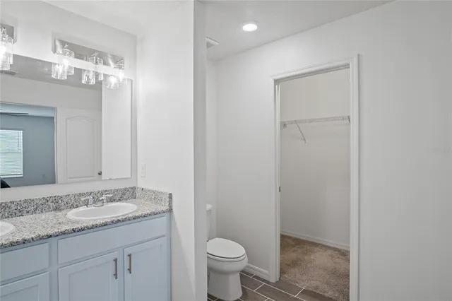 a bathroom with a granite countertop sink a toilet and a mirror