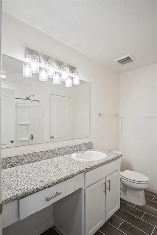 a bathroom with a granite countertop sink a toilet and a mirror