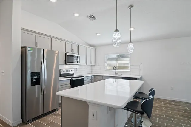 a kitchen with stainless steel appliances granite countertop a refrigerator a sink a stove and a refrigerator with wooden floor