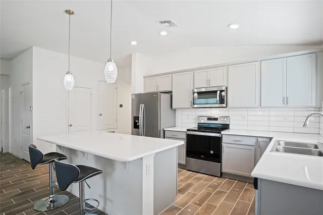 a kitchen with stainless steel appliances a stove a sink a microwave a refrigerator and cabinets