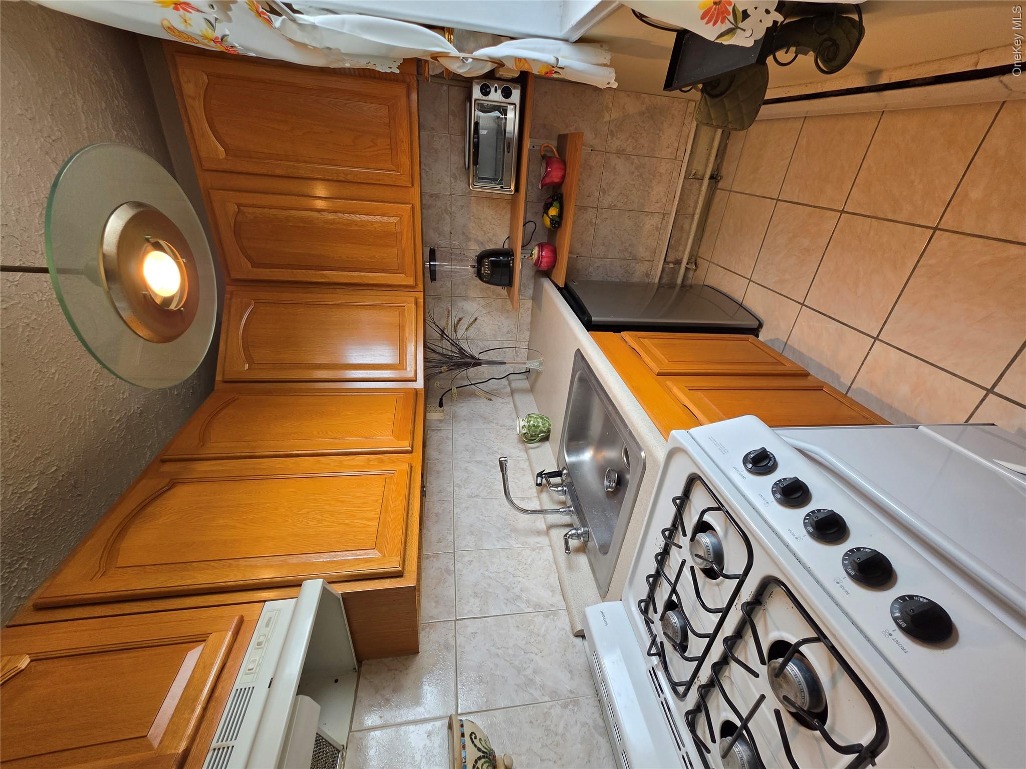 129 Beach 118th Street, Unit 5A Queens, NY 11694 - Photo 10 of 17 a kitchen with a stove a sink and a refrigerator