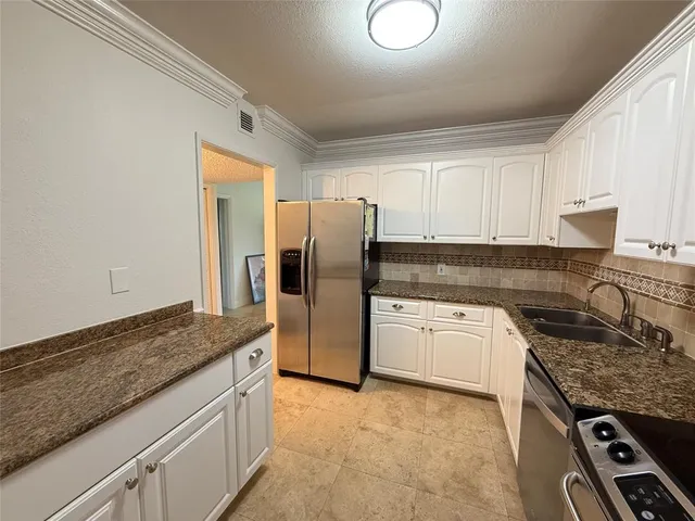 a kitchen with granite countertop a refrigerator stove and sink