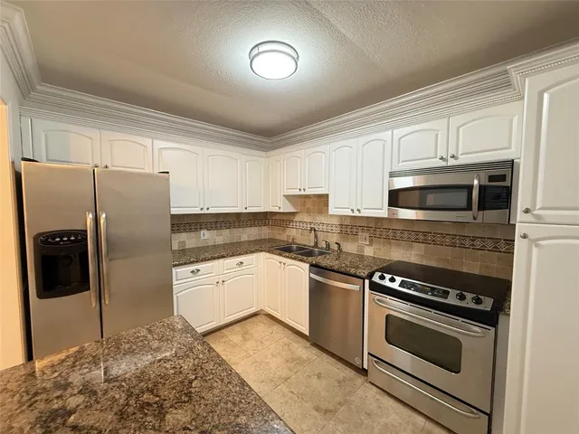 a kitchen with stainless steel appliances granite countertop a refrigerator stove and sink