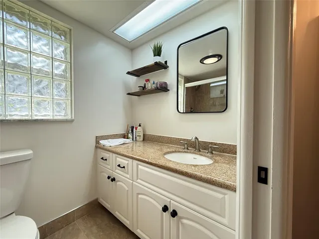 a bathroom with a granite countertop toilet sink and mirror