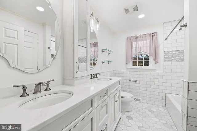 a bathroom with a granite countertop double vanity sink a mirror and a toilet
