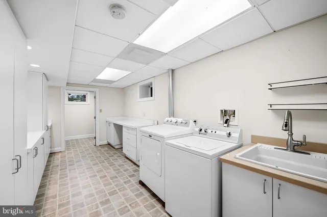 a view of a kitchen with a sink and dishwasher a refrigerator with white cabinets