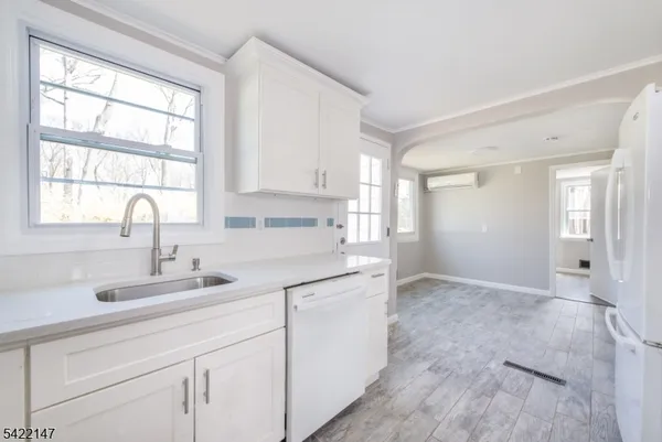 a kitchen with white cabinets appliances a sink and a window