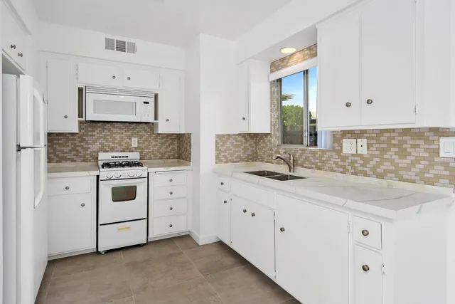 a kitchen with granite countertop white cabinets white stainless steel appliances with a sink and dishwasher
