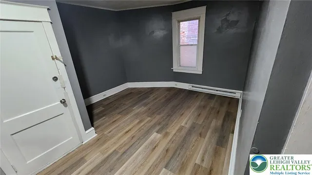 a view of an empty room with wooden floor and a window