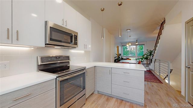a kitchen with white cabinets stainless steel appliances and wooden floor