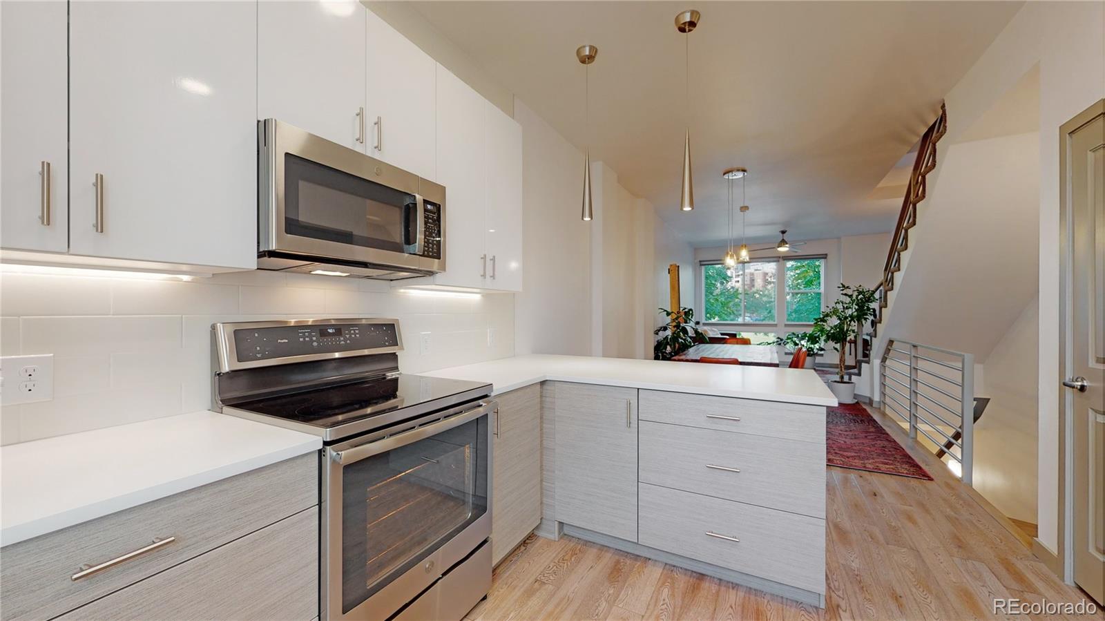 385 22nd Street, Unit 4 Denver, CO 80205 - Photo 15 of 40 a kitchen with white cabinets stainless steel appliances and wooden floor