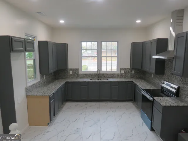 a kitchen with granite countertop a sink window and cabinets