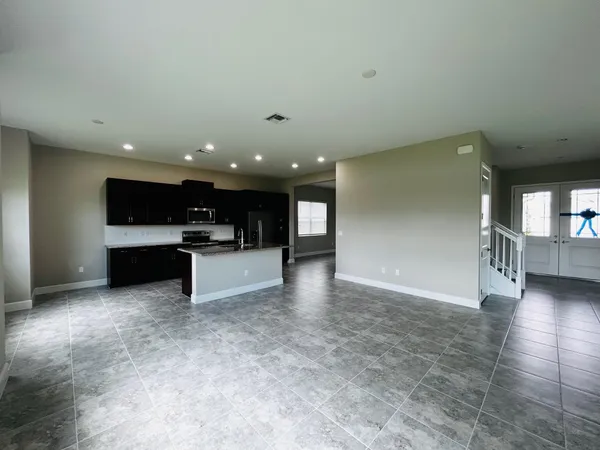 a living room with stainless steel appliances furniture a front door and a window