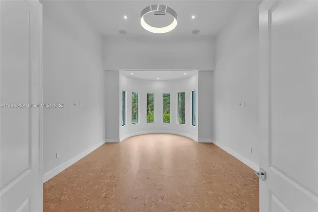 a view of an empty room with a window and a kitchen
