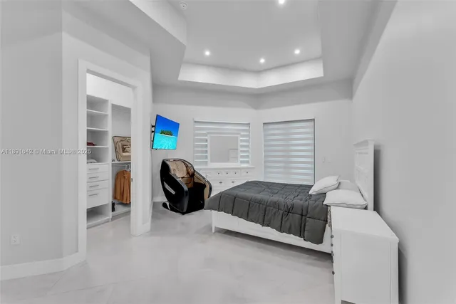 a bedroom with bed a couch and a flat tv screen on dresser