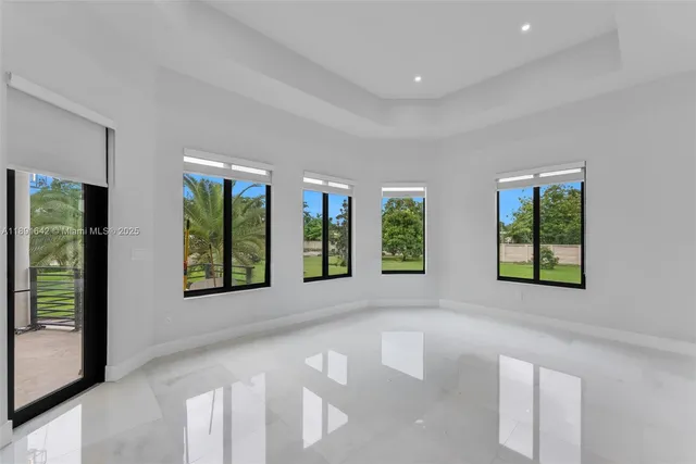 a view of an empty room with a window and kitchen view
