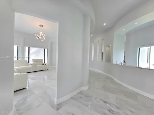 a view of a hallway with furniture and chandelier