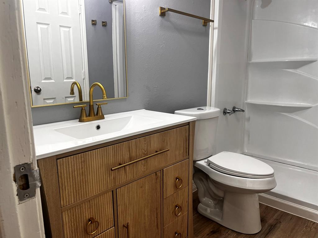 1007 Mack Place Denton, TX 76209 - Photo 21 of 37 Full bathroom with a textured wall, vanity, dark wood-style floors, and a shower