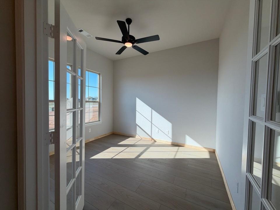 313 Johnny Boy Way Springtown, TX 76082 - Photo 3 of 11 Room featuring wood-finish flooring, two windows, and a ceiling fan with integrated lighting