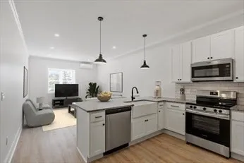 a kitchen with granite countertop a sink stainless steel appliances and white cabinets