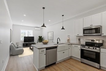 a kitchen with granite countertop a sink stainless steel appliances and white cabinets