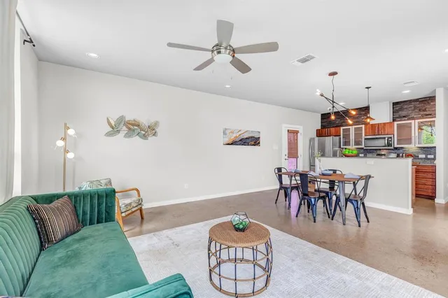 a living room with furniture kitchen view and a chandelier