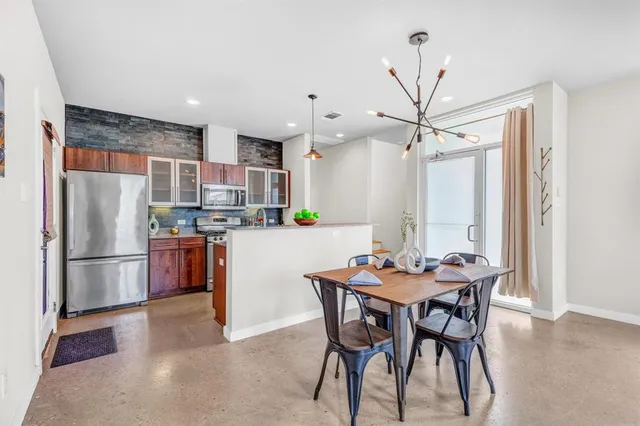 a kitchen with a refrigerator a dining table and chairs