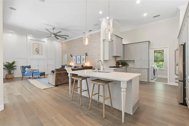 a open kitchen with stainless steel appliances kitchen island a stove a sink a dining table and chairs with wooden floor