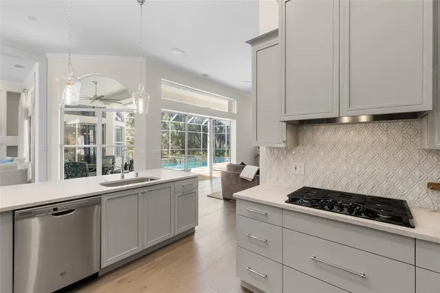 a kitchen with stainless steel appliances a sink a stove and white cabinets